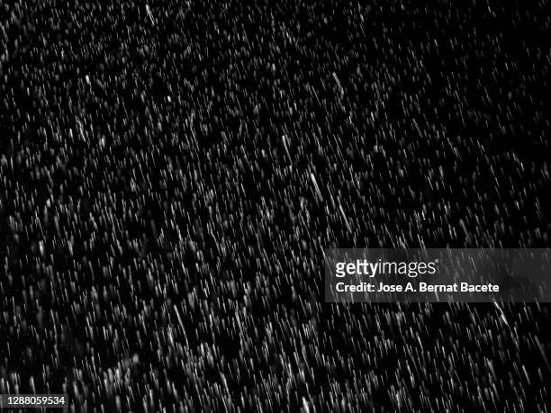 full frame of raindrops falling on a black background. - torrential rain stock pictures, royalty-free photos & images