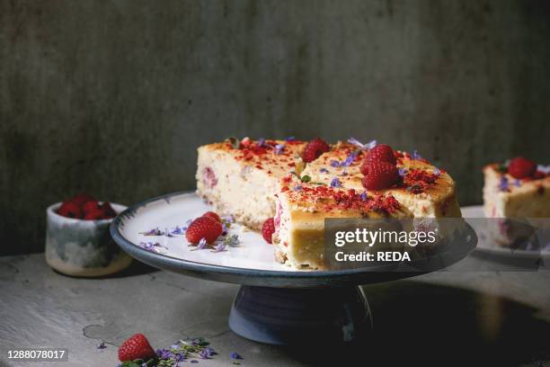 Homemade raspberry baked cheesecake sliced on plate decorated by fresh raspberries and mint on grey table. Flat lay. Space.