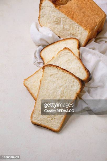 Sliced homemade Hokkaido wheat toast bread on white cloth on white texture background. Flat lay. Copy space.