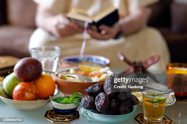 Traditional meal for iftar in time of Ramadan after the fast has been broken. Muslim reading Quran. France.