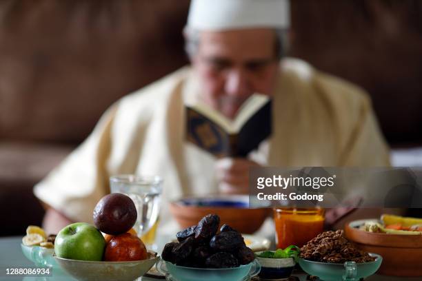 Traditional meal for iftar in time of Ramadan after the fast has been broken. Muslim reading Quran. France.