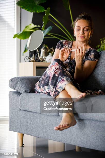 woman doing a manicure while relaxing on sofa - nail file stock pictures, royalty-free photos & images