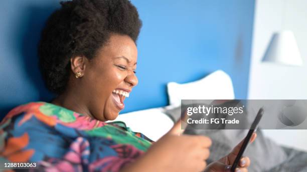 mujer haciendo una videollamada usando un teléfono inteligente en casa - plano fijo fotografías e imágenes de stock