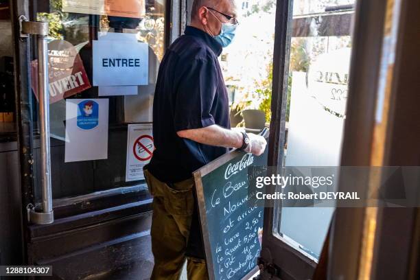 Un serveur sort en terrasse l'ardoise portant le menu du jour dans un vieux bar du quartier de la Croix-Rousse lors de la réouverture des restaurants...