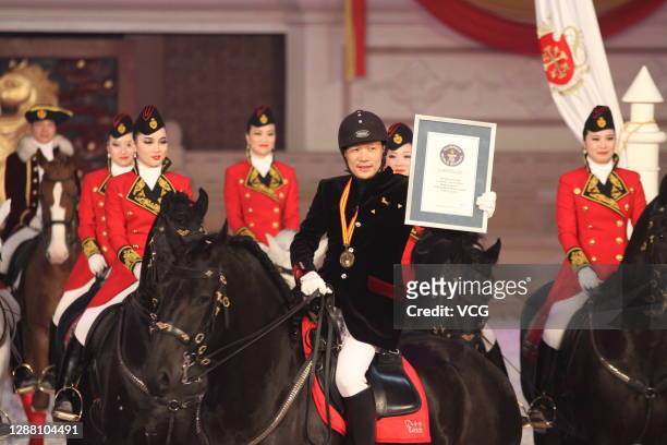 Zhou Jianping, Chairman of Heilan Group, poses with a certification after fifty-six riders and their horses set a new Guinness world record for...