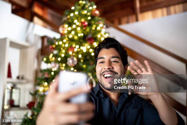 mens die een videovraag op smartphone doet die kerstboom toont - chat noel stockfoto's en -beelden