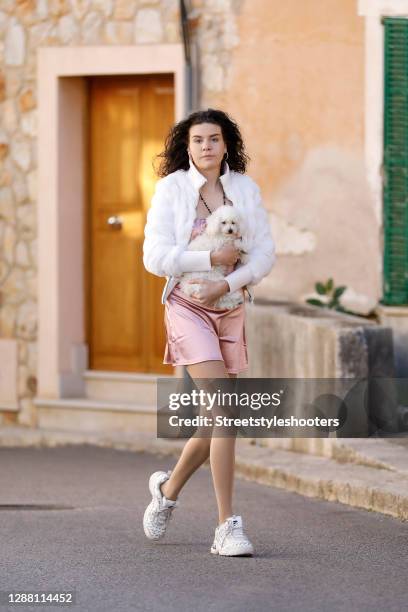 Spanish model Claire Alemany wearing a short light pink dress by H&M, white sneaker by Fila, a white fuzzy jacket and a black vintage rosary necklace...