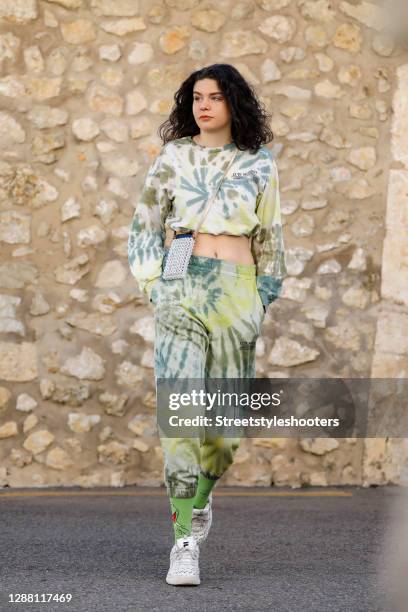 Spanish model Claire Alemany wearing a green and yellow tie dye sweat suit by Bershka, a phone pouch with iridescent beads, white sneaker by Fila and...