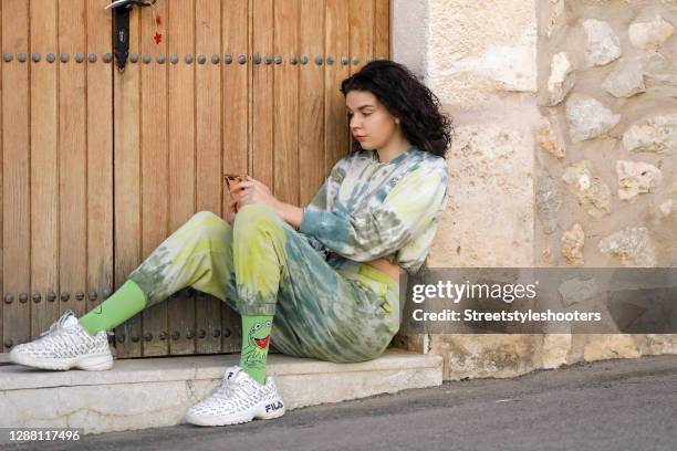 Spanish model Claire Alemany wearing a green and yellow tie dye sweat suit by Bershka, white sneaker by Fila and green kermit the frog socks by H&M...