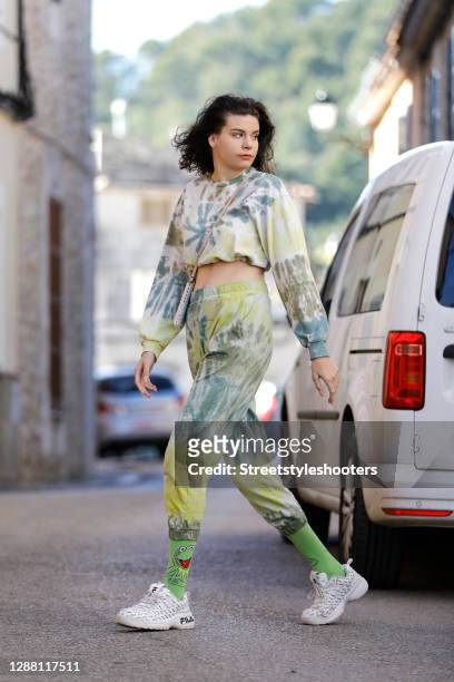 Spanish model Claire Alemany wearing a green and yellow tie dye sweat suit by Bershka, a phone pouch with iridescent beads, white sneaker by Fila and...