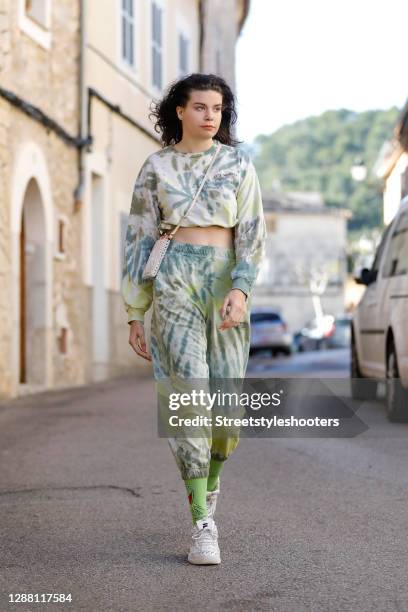 Spanish model Claire Alemany wearing a green and yellow tie dye sweat suit by Bershka, a phone pouch with iridescent beads, white sneaker by Fila and...