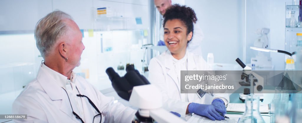 Multi ethnic laboratory team celebrating breakthrough in research. Smiling