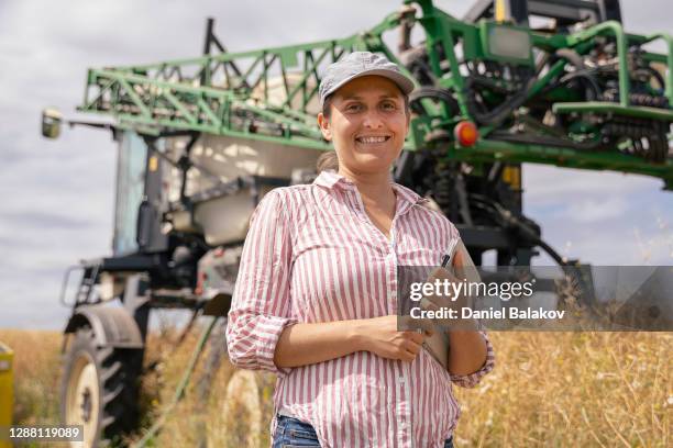 portrait of smiling farmer woman, crop sprayer behind. agricultural concept. - farm worker woman stock pictures, royalty-free photos & images