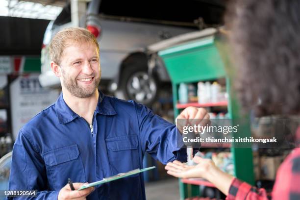 customer woman receives her car keys from automobile mechanic after he has repaired her vehicle. - auto mechaniker stock-fotos und bilder