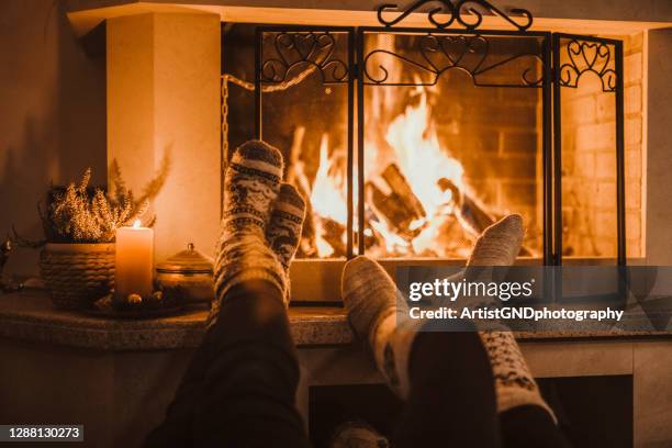couple enjoying christmas near fireplace. - cosy fireplace stock pictures, royalty-free photos & images