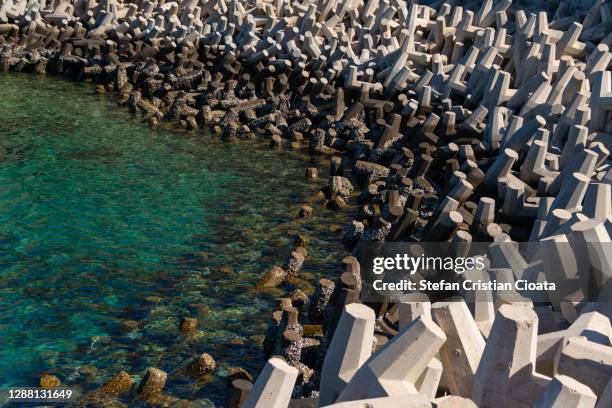 tetrapods on muscat coastline near corniche, oman - construction barrier stock-fotos und bilder