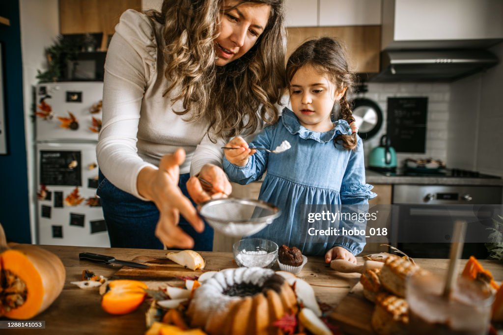 Mãe e filha na cozinha espaing bolo com açúcar em pó