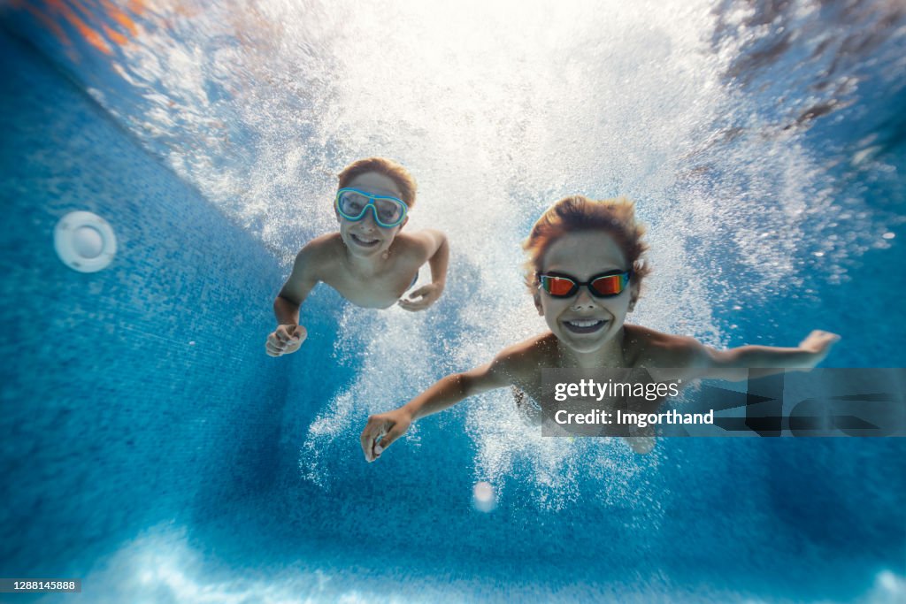 Kids swimming underwater in pool