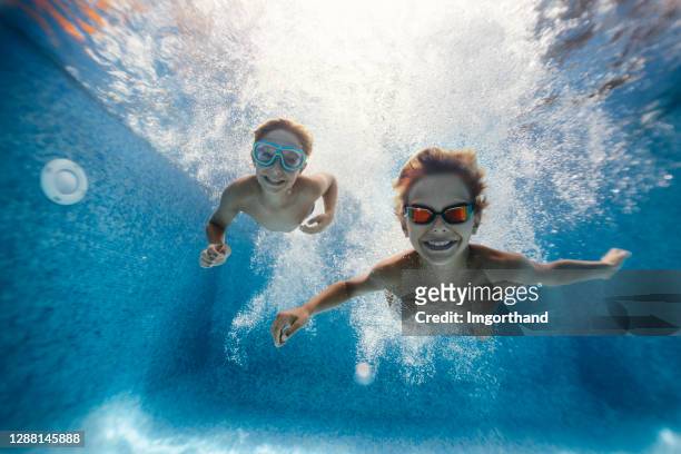 kids swimming underwater in pool - catching bubbles stock pictures, royalty-free photos & images