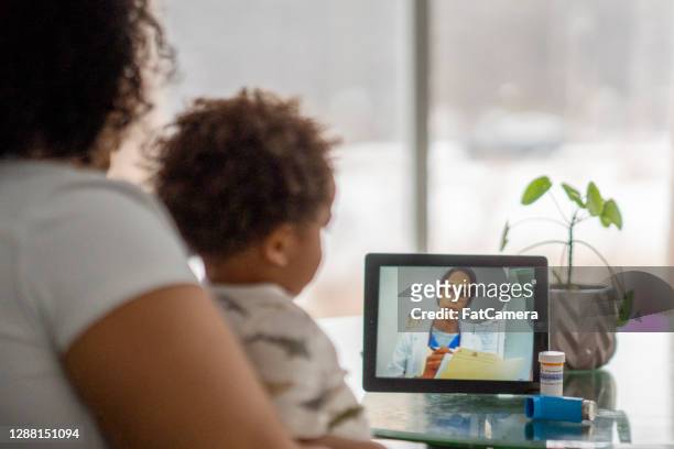 mother on a remote medical call with a doctor about her sick child - visit stock pictures, royalty-free photos & images