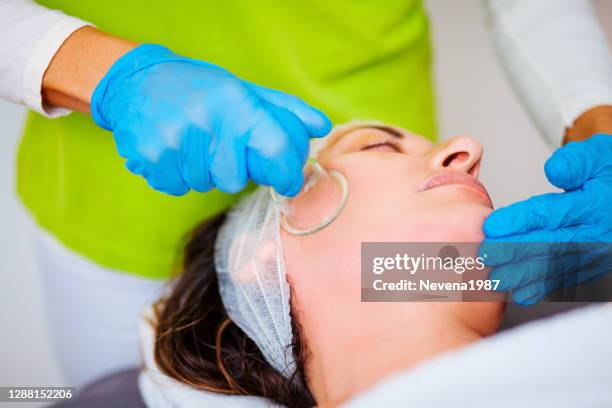 the cosmetologist makes the procedure vacuum face cleaning of a beautiful, young woman in a beauty salon - capillary body part stock pictures, royalty-free photos & images
