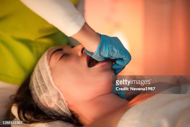 de fysiotherapeut maakt gezichtsmassage die aan de kaak van de vrouw in schoonheidskliniek werkt - human jaw bone stockfoto's en -beelden