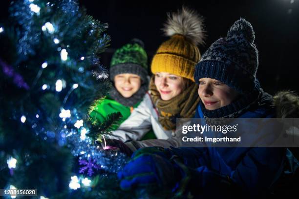 kids decorating christmas tree outdoors - christmas dark stock pictures, royalty-free photos & images