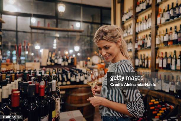 woman tasting wine in a wine shop - buying alcohol stock pictures, royalty-free photos & images