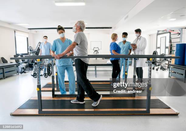 group of doctors and patients in a physiotherapy center wearing facemasks - coronavirus recovery stock pictures, royalty-free photos & images