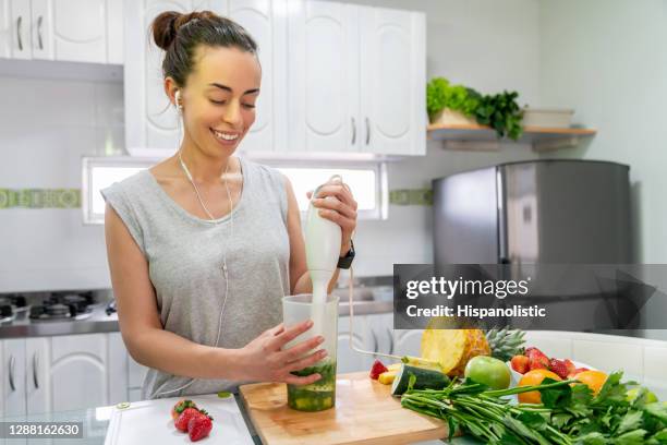 porträt einer gesunden frau zu hause, die einen grünen smoothie macht - blender stock-fotos und bilder