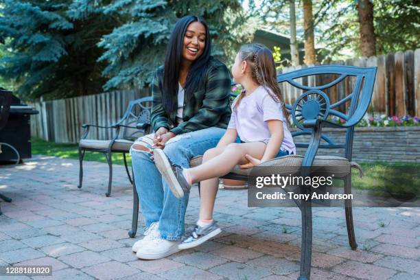 young woman and small girl sitting on bench in back yard - baby sitting stock pictures, royalty-free photos & images