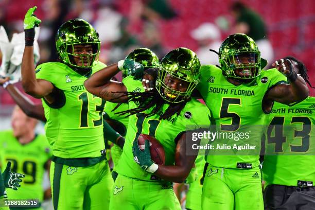 Dwayne Boyles celebrates with Tramel Logan and Antonio Grier of the South Florida Bulls after Boyles intercepted a pass thrown by Dillon Gabriel of...