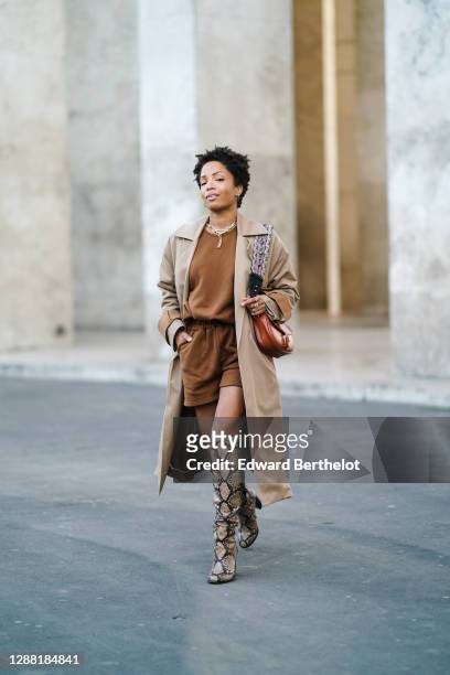 Ellie Delphine wears a necklace, a beige long trench coat from King Tuckfield, a brown wool top and brown shorts from Frankie Shop, a Dior bag made...