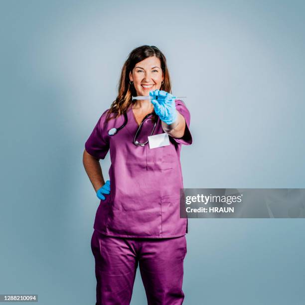 fröhliche reife ärztin hält spritze - surgeon holding needle stock-fotos und bilder