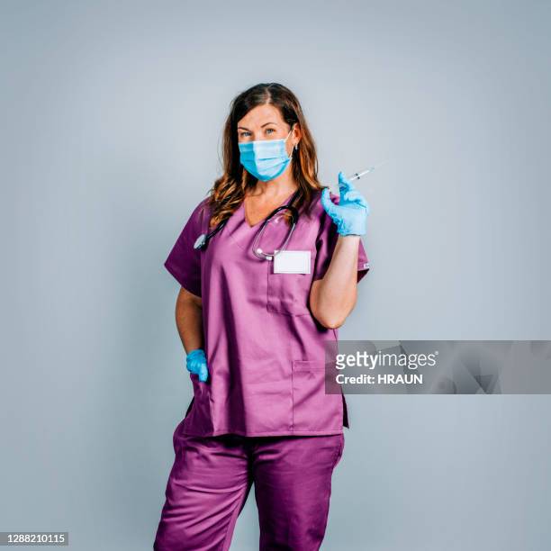 weibliche krankenschwester haltespritze während covid-19 - surgeon holding needle stock-fotos und bilder