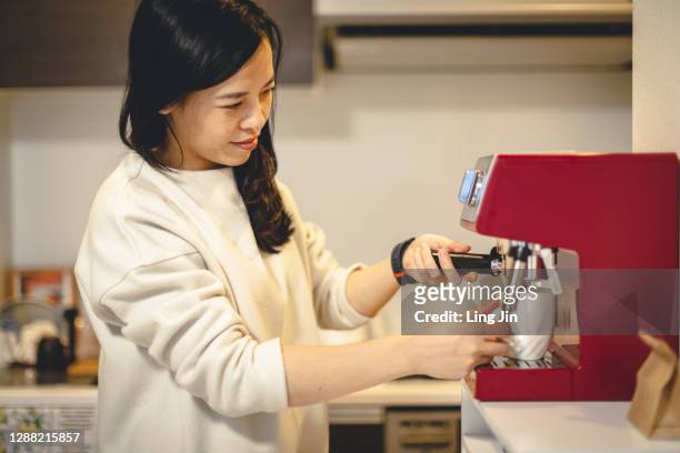 asian woman making coffee at home using espresso maker - espressomachine stockfoto's en -beelden