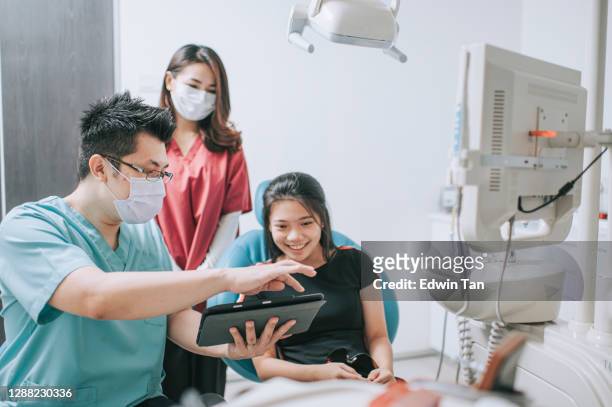 asian chinese male dentist explaining tooth x-rays to a patient - dentist office stock pictures, royalty-free photos & images