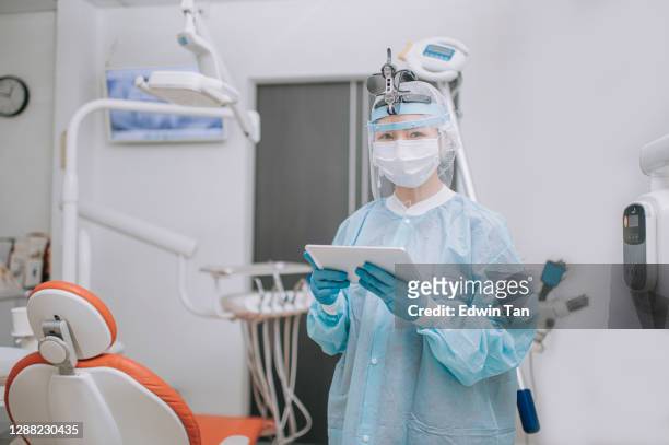 亞洲中國牙醫與 ppe 防護工作服拿著數位平��板電腦在牙醫的辦公室看相機 - face shield 個照片及圖片檔