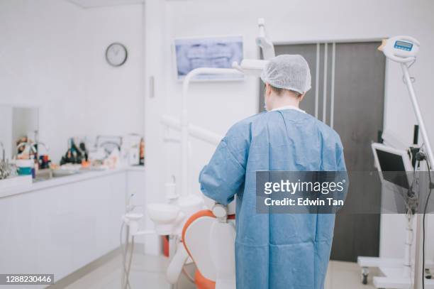 rear view of asian chinese dentist performing a surgery on patient in dentist's office - root canal stock pictures, royalty-free photos & images