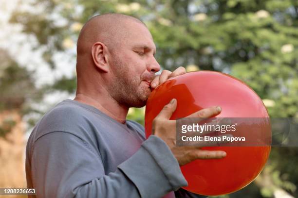 adult brutal man blowing ballon - blowing up balloon stock pictures, royalty-free photos & images