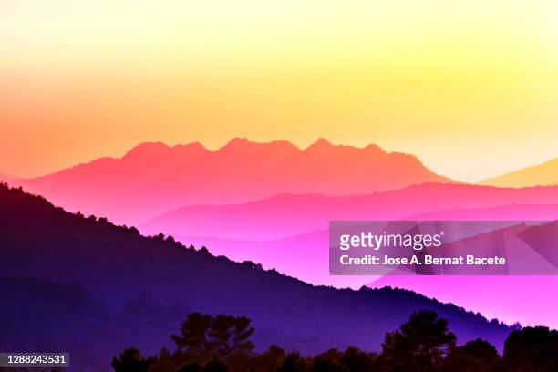 silhouettes of mountains between covered valleys of fogs and hazes at sunset. - cirrus stockfoto's en -beelden