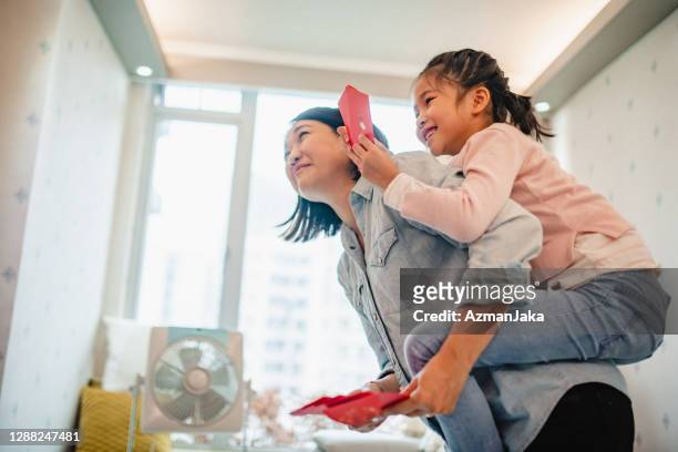chinese mother and young daughter holding red envelopes - 2018 chinese new year stock pictures, royalty-free photos & images