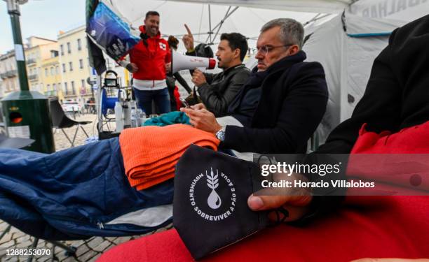 Protective mask with the movement logo is displayed as members of the "A Pão e Água" movement sit in front of tents as they stage a hunger strike...