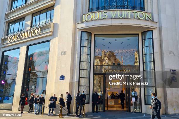 Customers wearing protective face masks queue in front of 'Louis Vuitton' flagship store on Champs-Elysées Avenue during its reopening this morning...