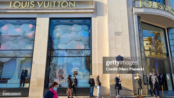 Customers wearing protective face masks queue in front of 'Louis Vuitton' flagship store on Champs-Elysées Avenue during its reopening this morning...