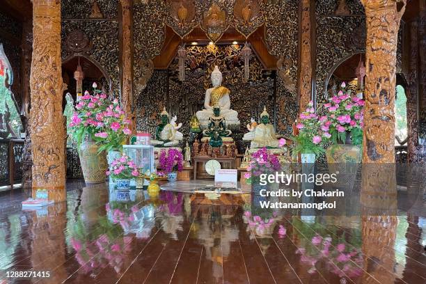 pong nam ron travel destinations - wooden chapel of wat khao chawang temple (interior) with beautiful wood craving, marble buddha statue and flower decoration. - jade stock pictures, royalty-free photos & images