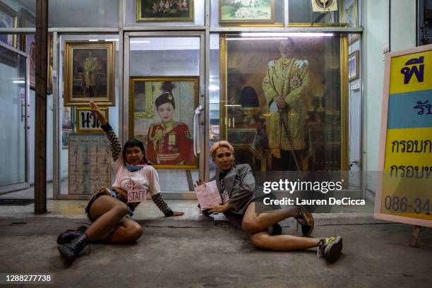 Thai pro-democracy protesters hold up a three finger salute in front of a portrait of King Rama X on November 28, 2020 in Bangkok, Thailand....