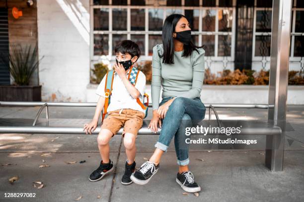 madre e hijo sentados en la estación de autobuses - flu mask in mexico fotografías e imágenes de stock