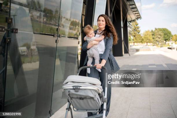 自信を持って母親と彼女の赤ちゃんが散歩をしている - supermom ストックフォトと画像
