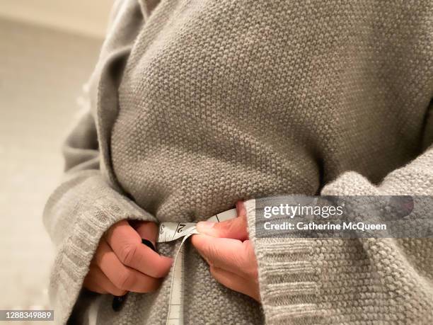 african-american woman uses a flexible measuring tape to measure waist - woman waist up stock pictures, royalty-free photos & images